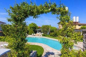 A swimming pool surrounded by lush greenery and stone pathways.