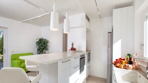Une cuisine moderne dotée d’un îlot central, de meubles blancs et d’un aménagement lumineux et aéré.