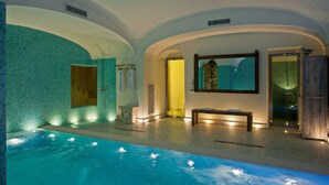 Un'area benessere con piscina, una panca e uno specchio.