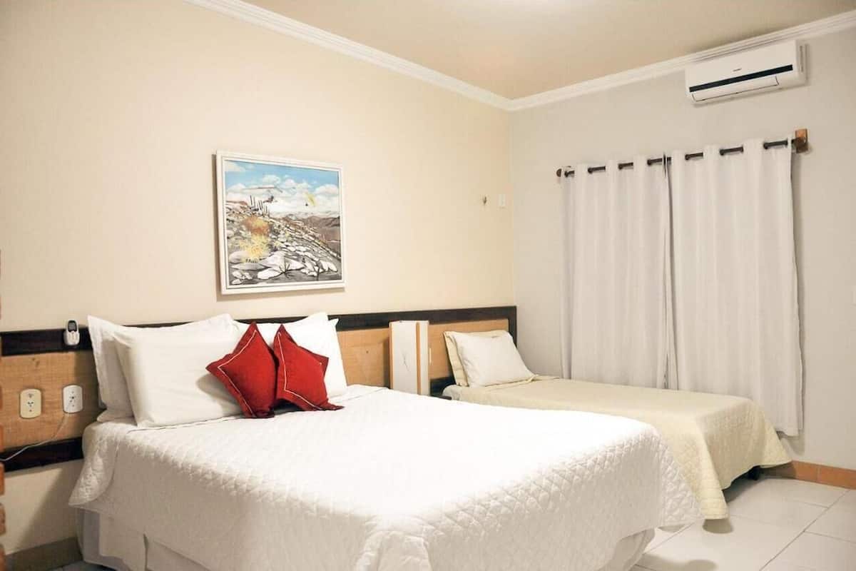 Una habitación de hotel con dos camas, un cuadro en la pared y un equipo de aire acondicionado.