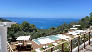 Une piscine sur le toit, dotée de chaises longues et de parasols, offrant une vue imprenable sur la côte.