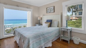 A bedroom with a large bed, a nightstand, a lamp, and a view of the ocean. - Gulf Front With Private Pool, Sleeps 21, Amazing Decks, Free Beach Setup! (Santa Rosa Beach)