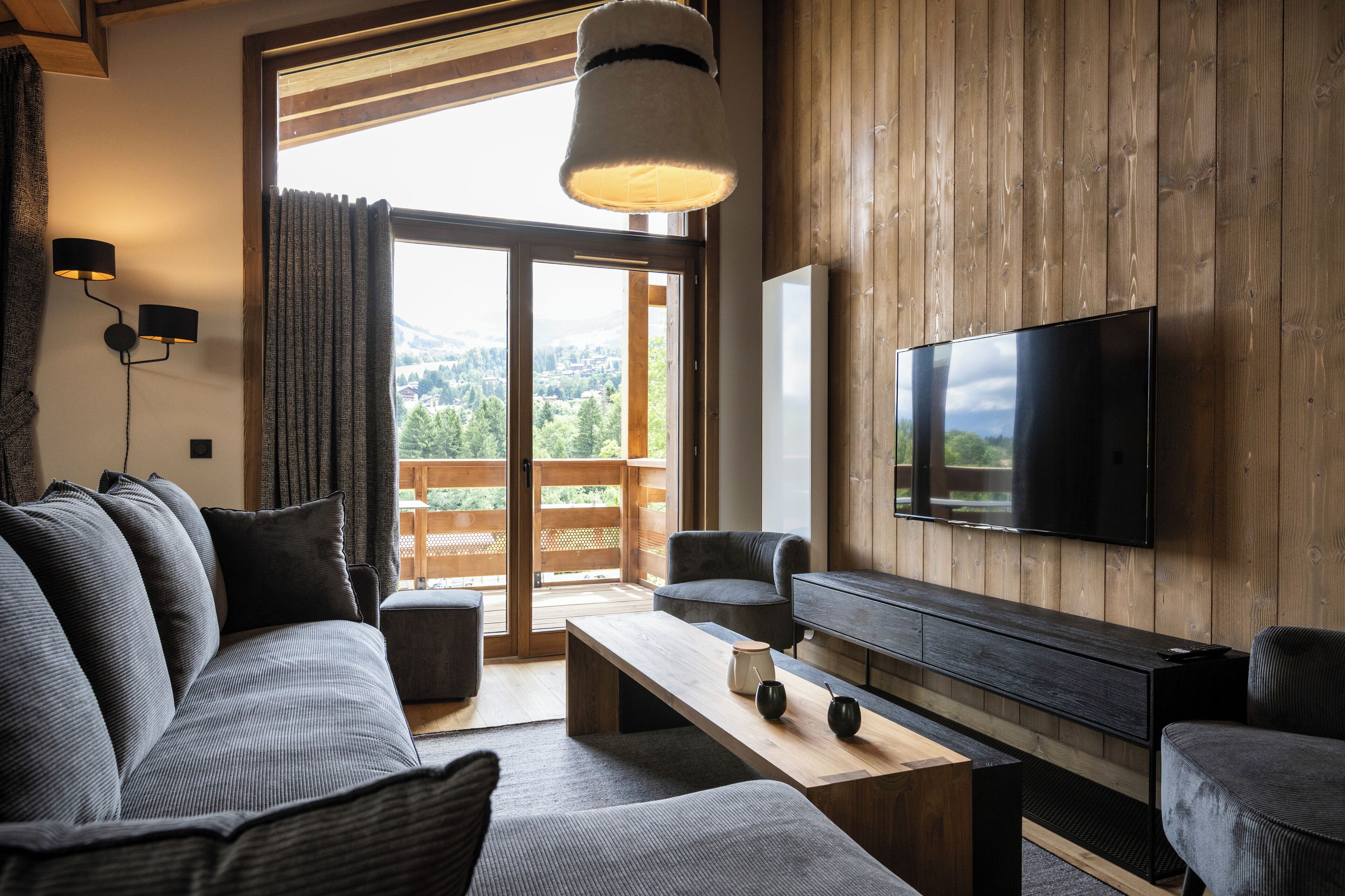 A modern living room with a large flat-screen TV, a sofa, a coffee table, and a wooden accent wall.