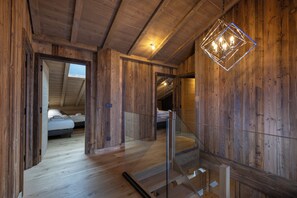 Interior de madera con una escalera, una cama y una lámpara colgante.