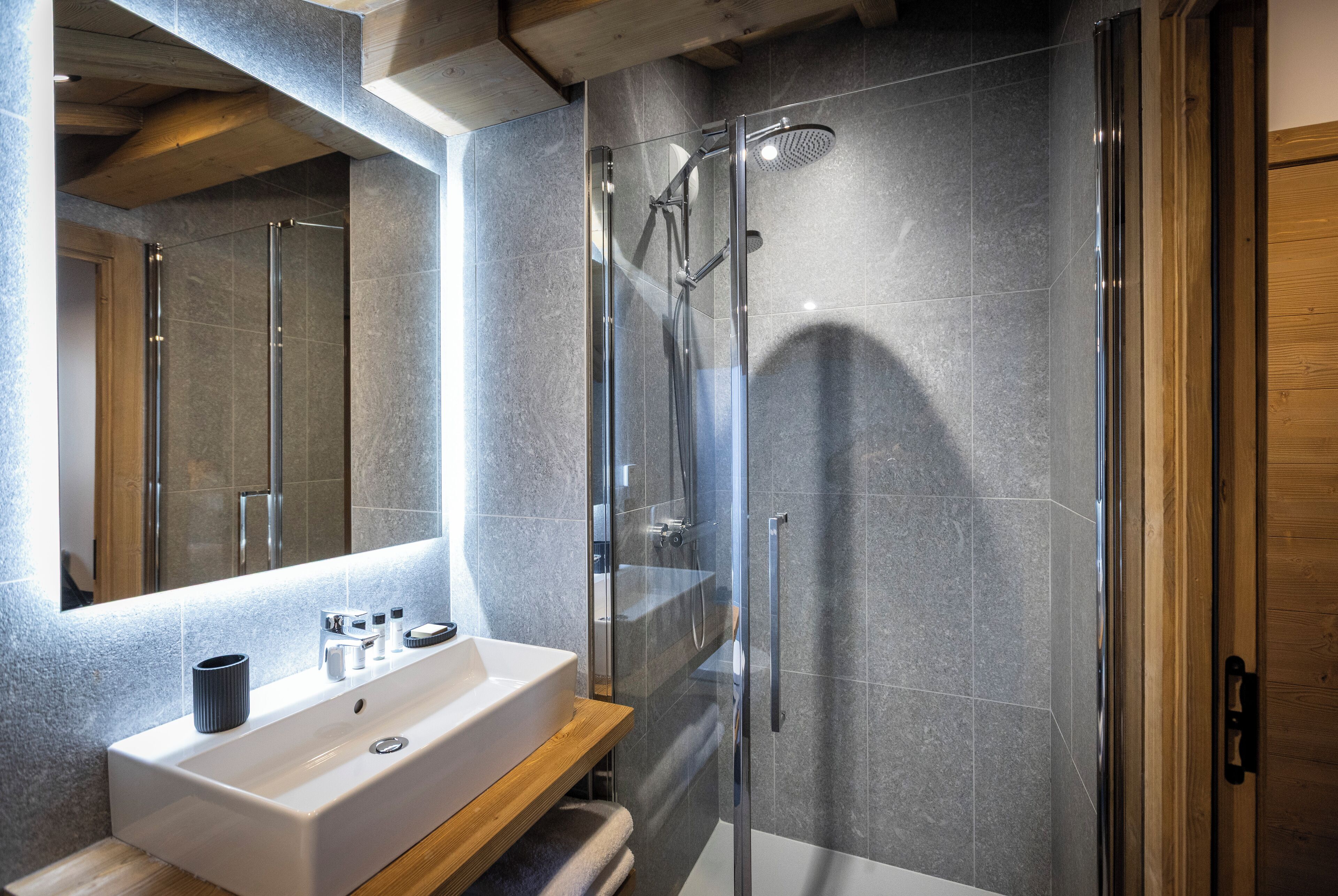A modern bathroom with a glass-enclosed shower, a white sink, and a wooden vanity.