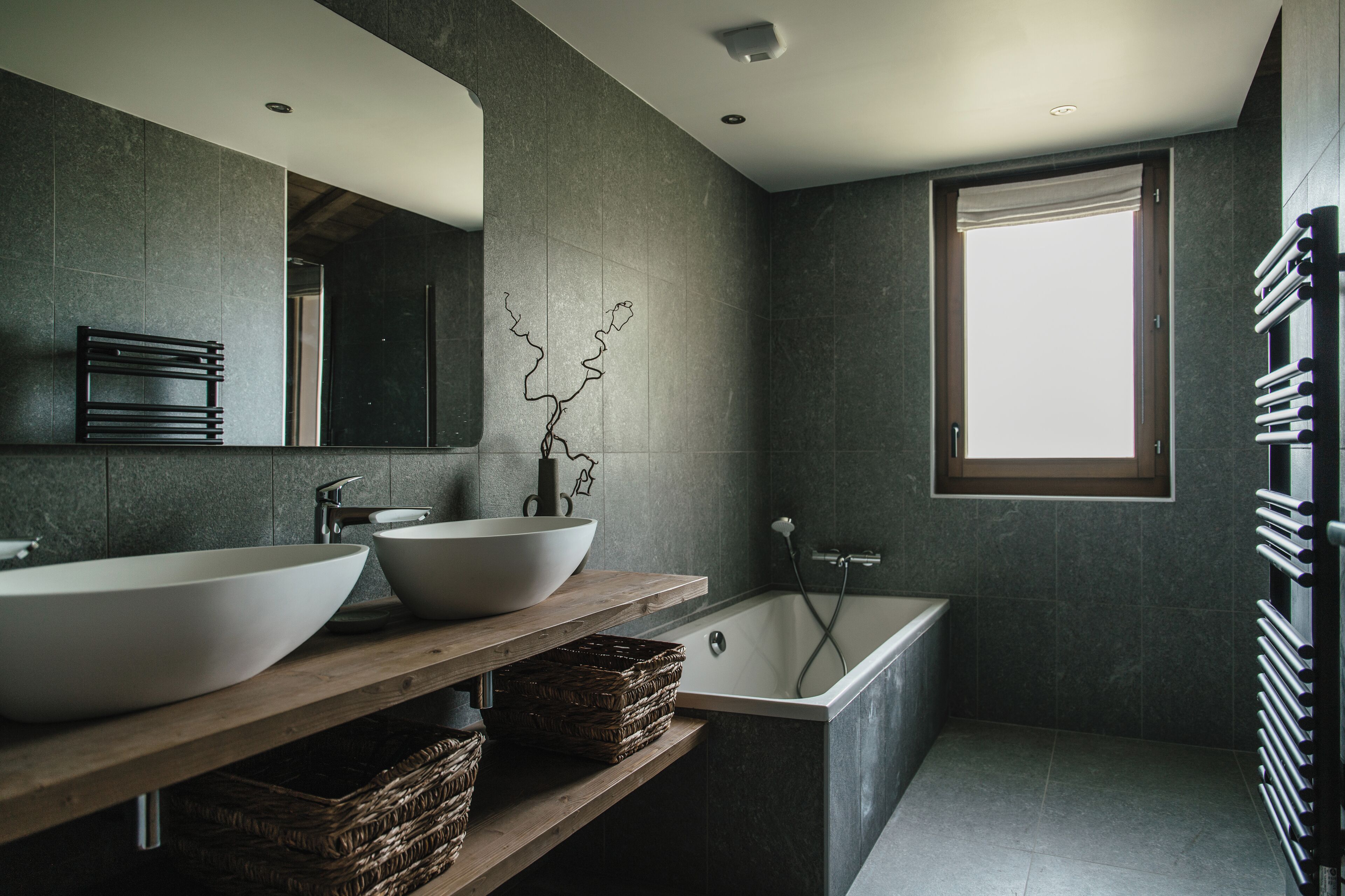 Une salle de bain moderne avec deux grands lavabos blancs, une baignoire sur pieds et un grand miroir au-dessus des lavabos.