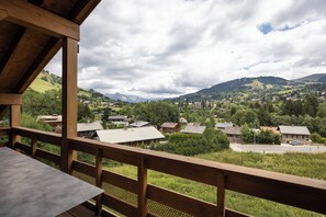Un balcón de madera con vistas a un pueblo y montañas.