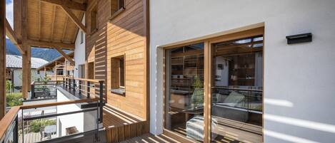Une terrasse en bois dotée d’une balustrade en verre, d’un escalier en bois et offrant une vue sur le paysage environnant.