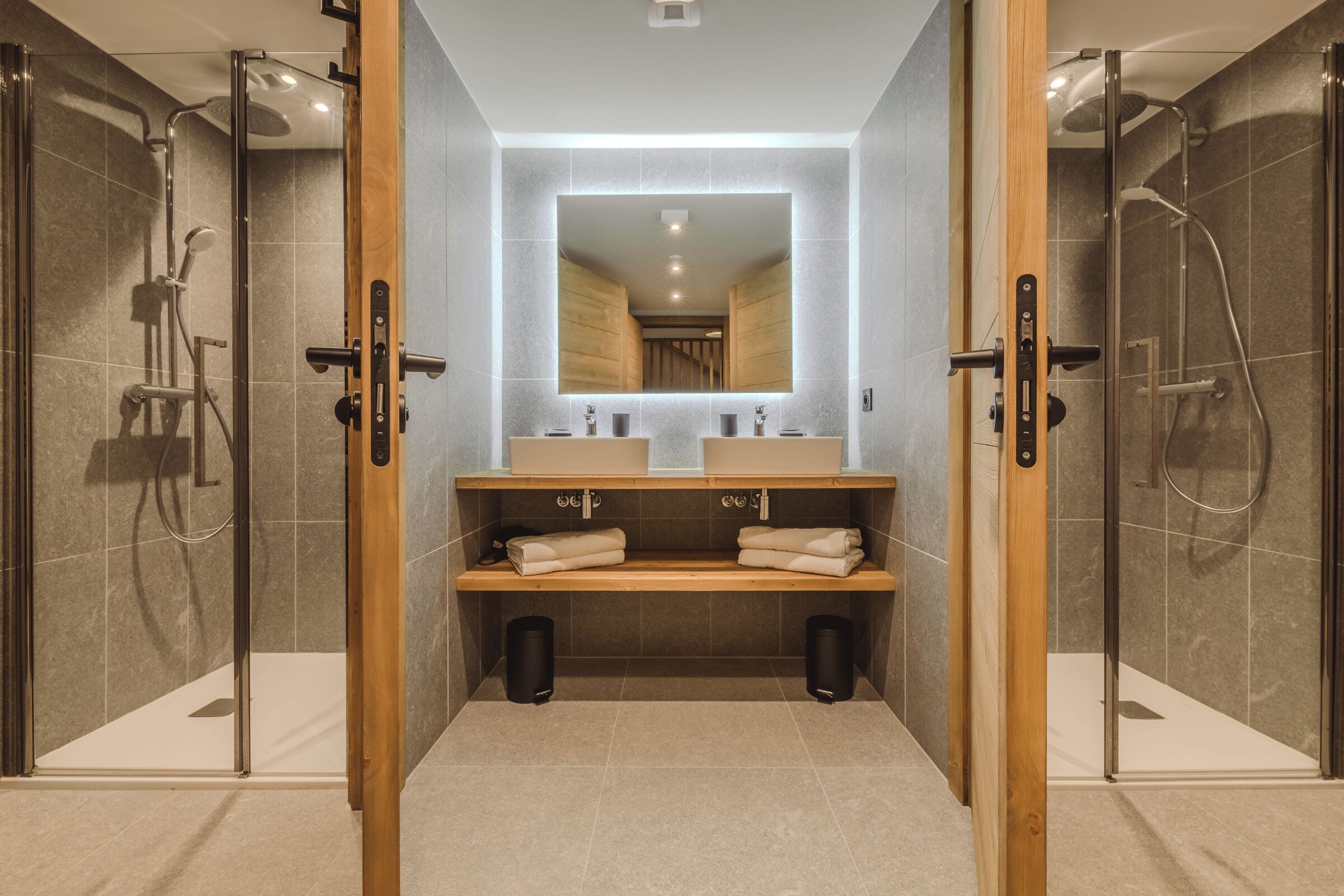 A modern bathroom with a glass-enclosed shower, two sinks, and a large mirror.