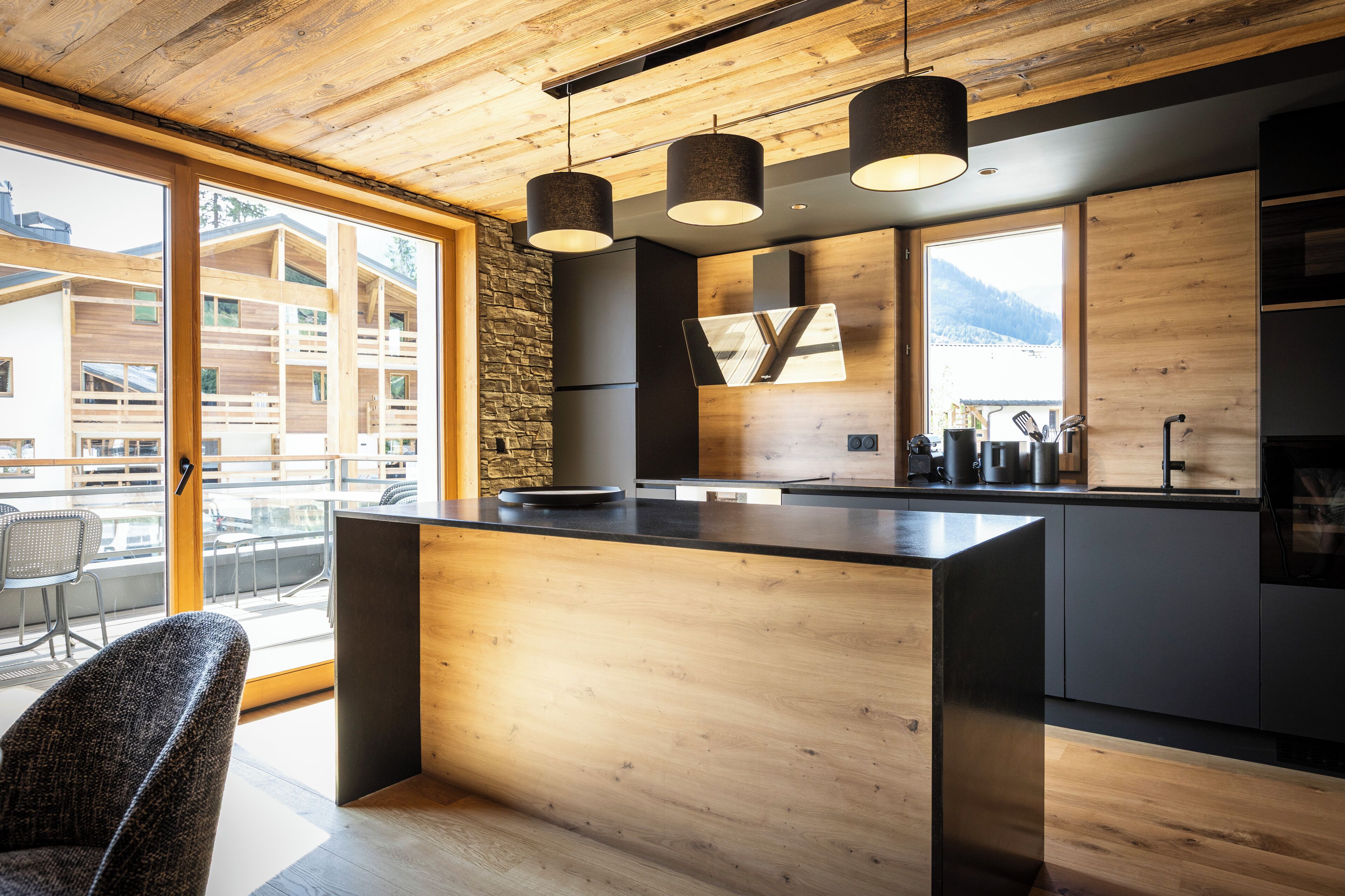Eine moderne Küche mit Holzelementen, einer großen Kochinsel und Bergblick.