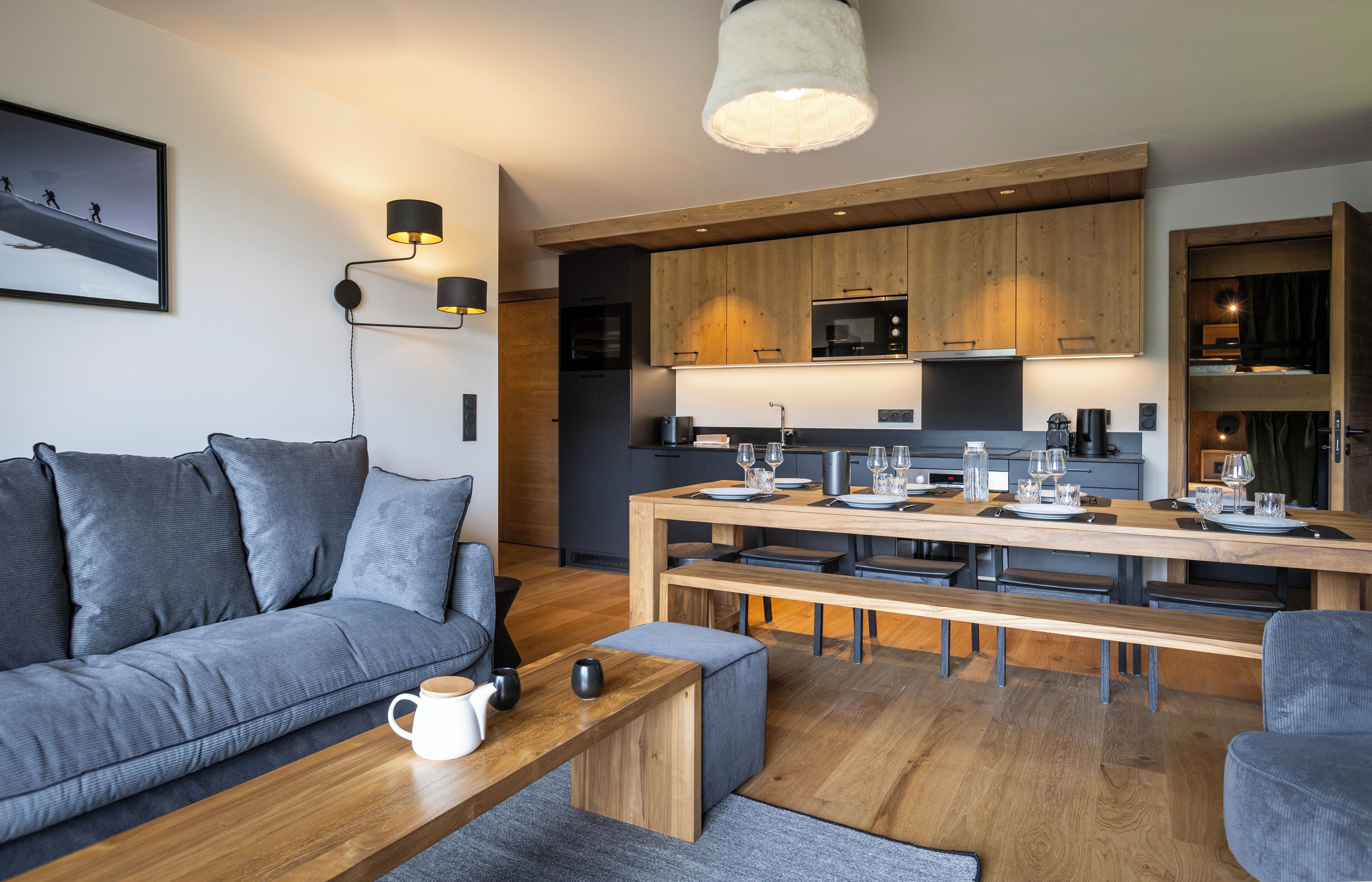 Una sala de estar moderna con sofá, mesa de centro y comedor con una mesa de madera dispuesta para cuatro comensales.