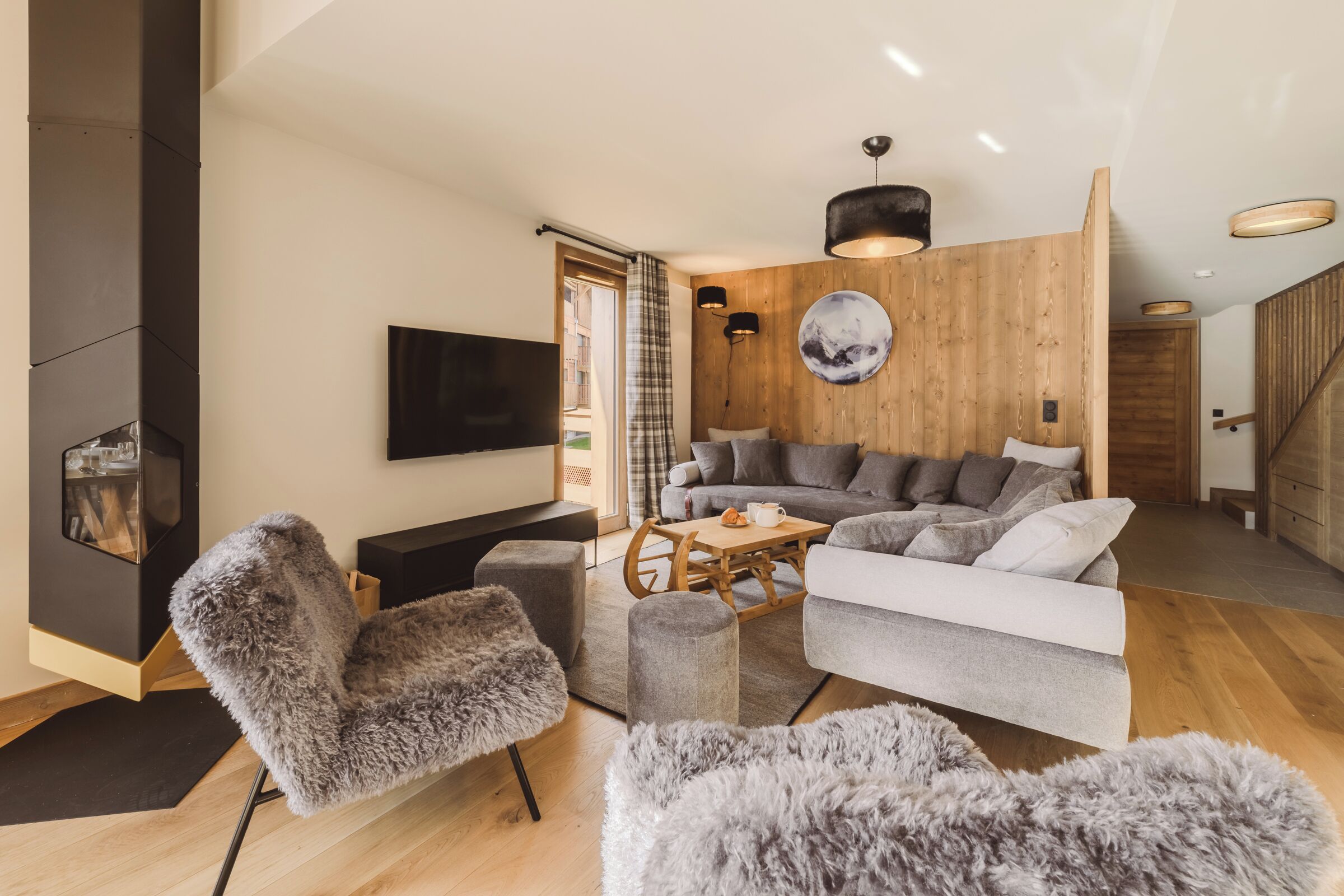 Una sala de estar moderna con un sofá, sillones, una mesa de centro y un televisor de pantalla plana.