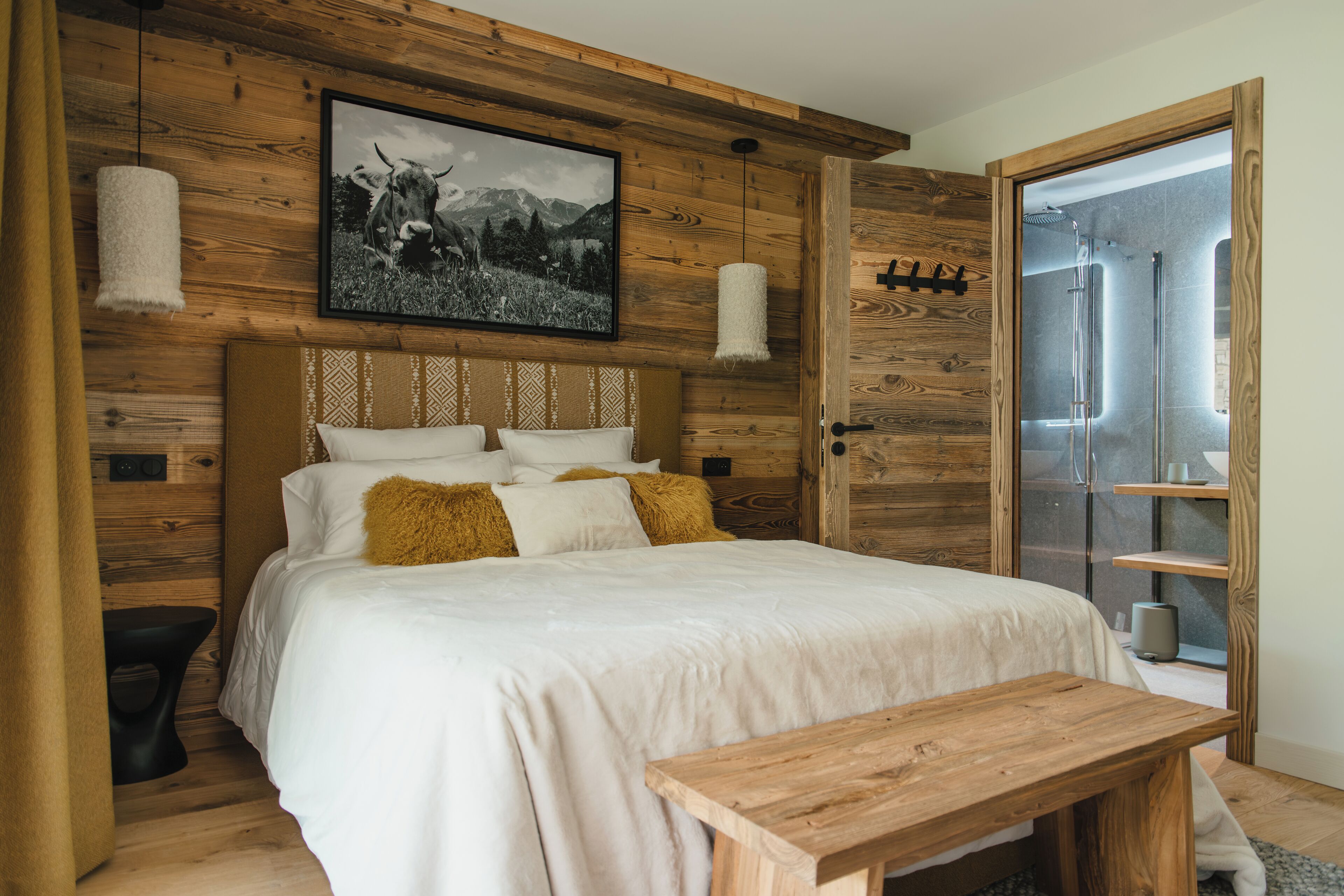 A wooden-paneled bedroom with a bed, a wooden bench, and a framed picture on the wall.
