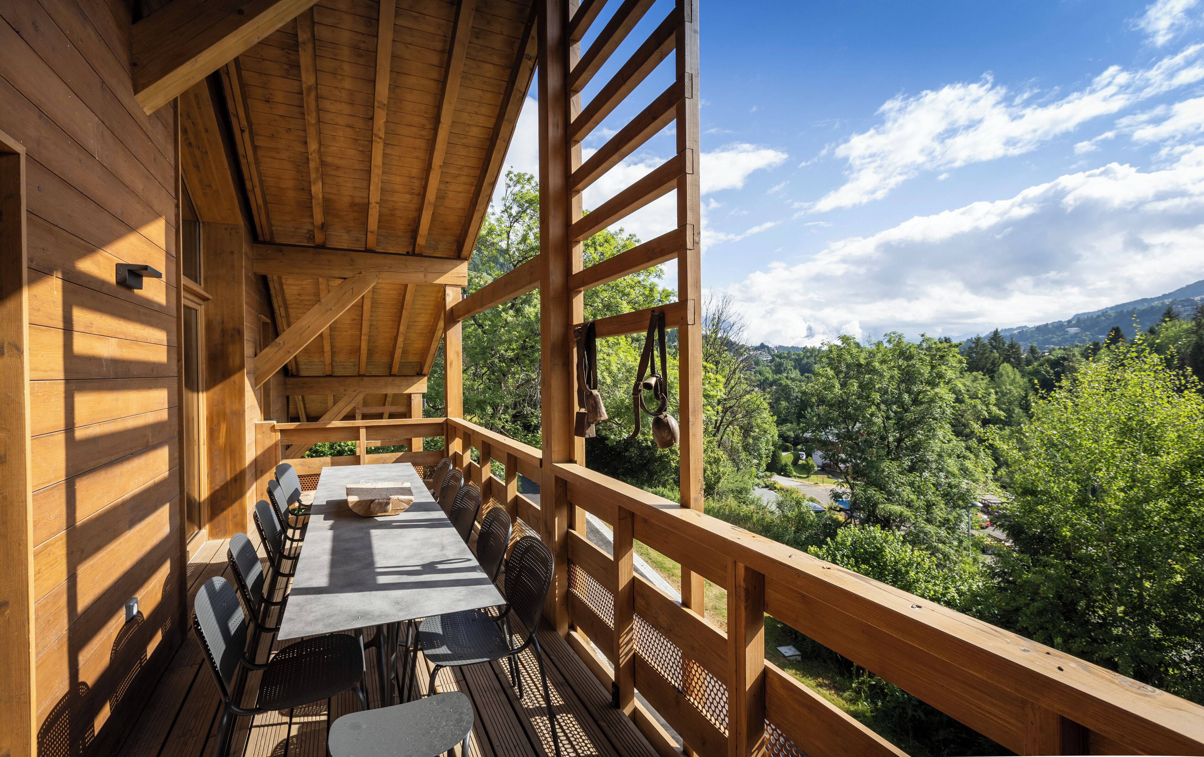 A wooden deck with a table and chairs, overlooking a forested valley.