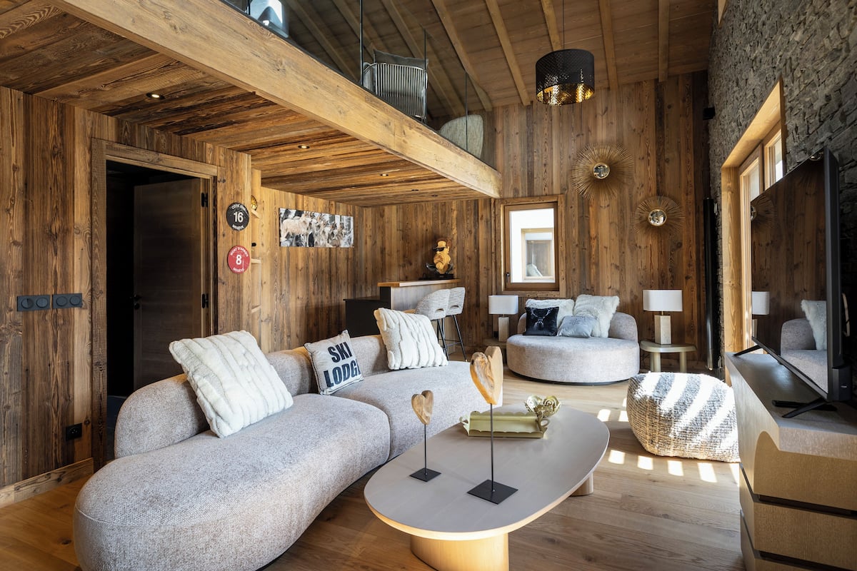 A wooden interior with a sofa, a coffee table, and a television.