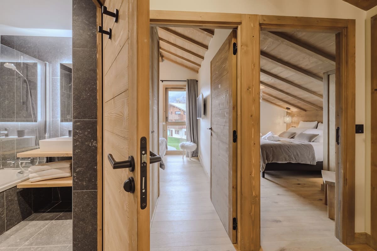 A hallway leading to a bedroom with a bed, a bench, and a view of the outdoors.