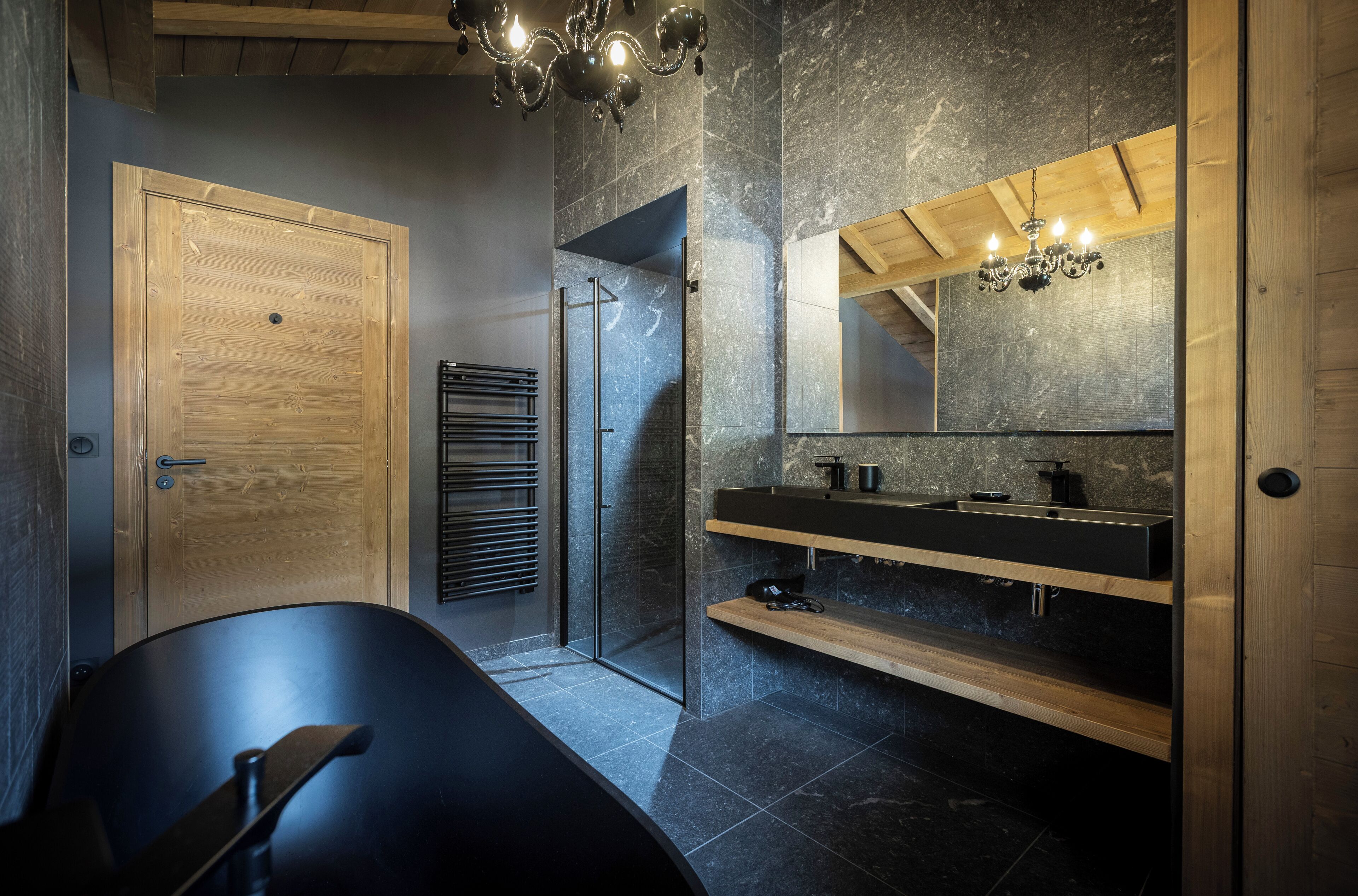 A modern bathroom with a freestanding bathtub, a glass shower enclosure, and a wooden vanity with a mirror.