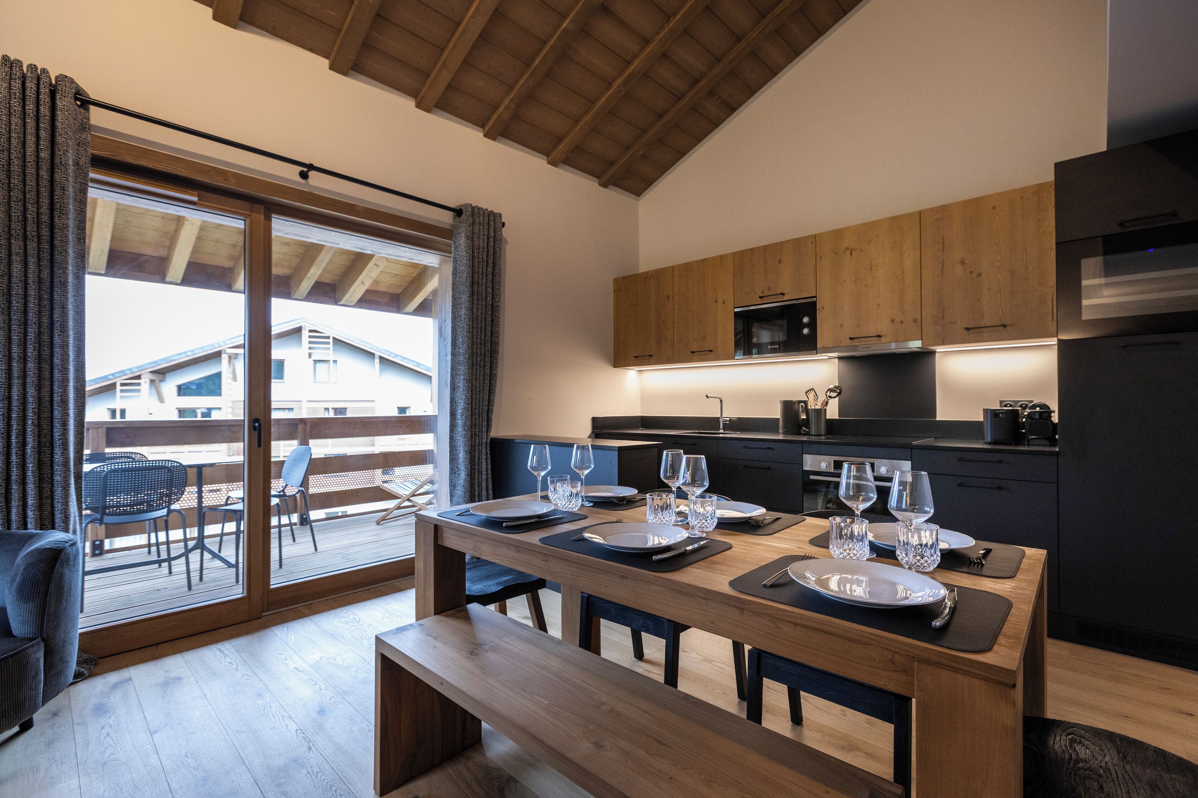 A modern kitchen with wooden cabinets, a built-in oven, and a dining area with a wooden table set for four.