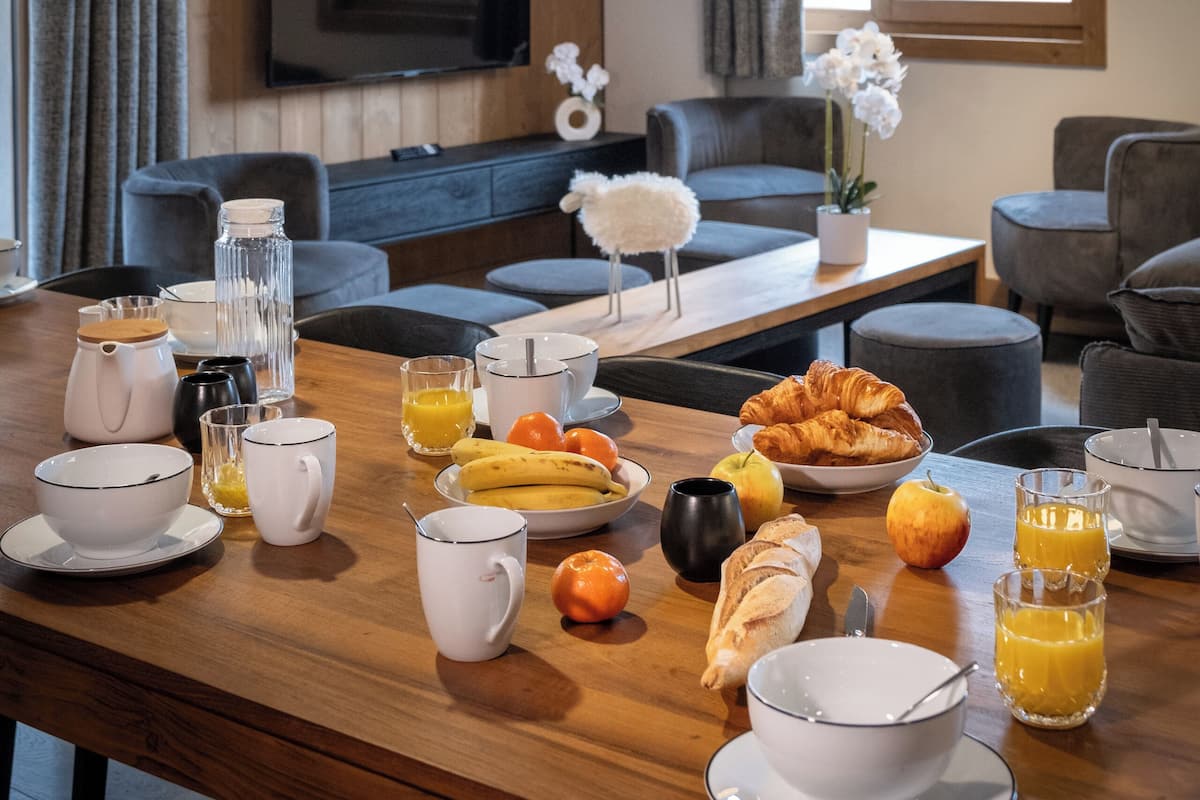 A breakfast setup with a wooden table, breakfast items, and a TV in a room with wooden walls and a modern design.