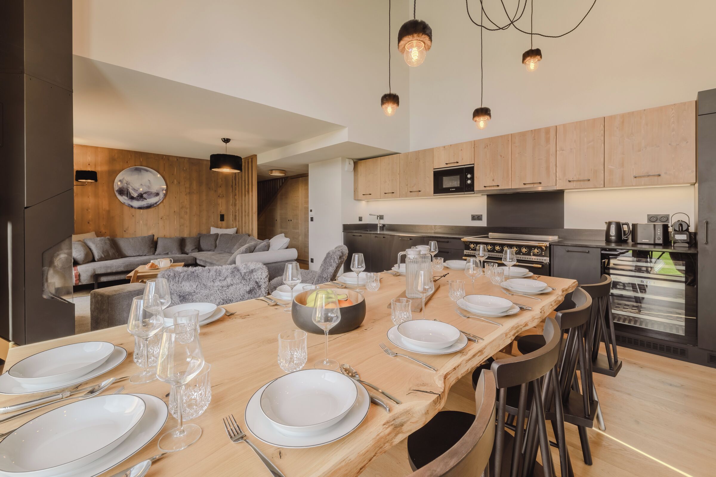 A modern kitchen with wooden cabinets, a built-in oven, and a dining area set for six with a wooden table and six chairs.