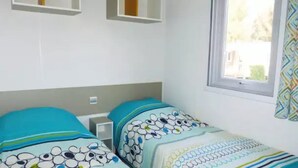 Un dormitorio con dos camas, cada una con ropa de cama estampada, una ventana con vistas y una mesita de noche.