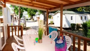 Un espacio de estar al aire libre cubierto con una mesa y sillas, rodeado de una terraza de madera.