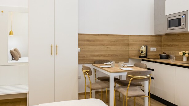 Ein modernes, minimalistisches Schlafzimmer mit Bett, Nachttisch und Beistelltisch.