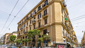 Ein mehrgeschossiges Gebäude mit Balkonen, eine Straße davor und geparkte Autos.