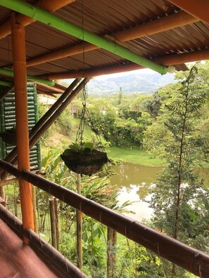 A rustic wooden structure with a view of a lush green landscape and a body of water. - Ecocabañas Pereira (Pereira)