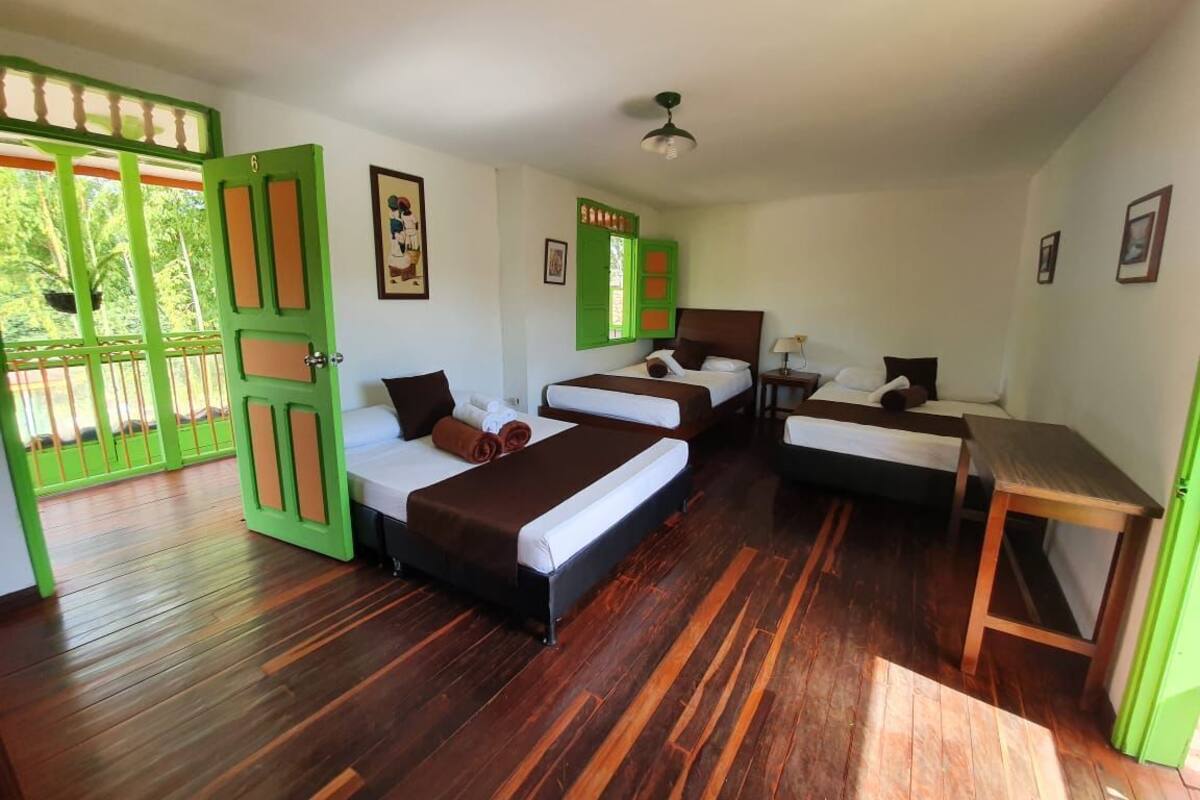 A room with three beds, a desk, and a green door.