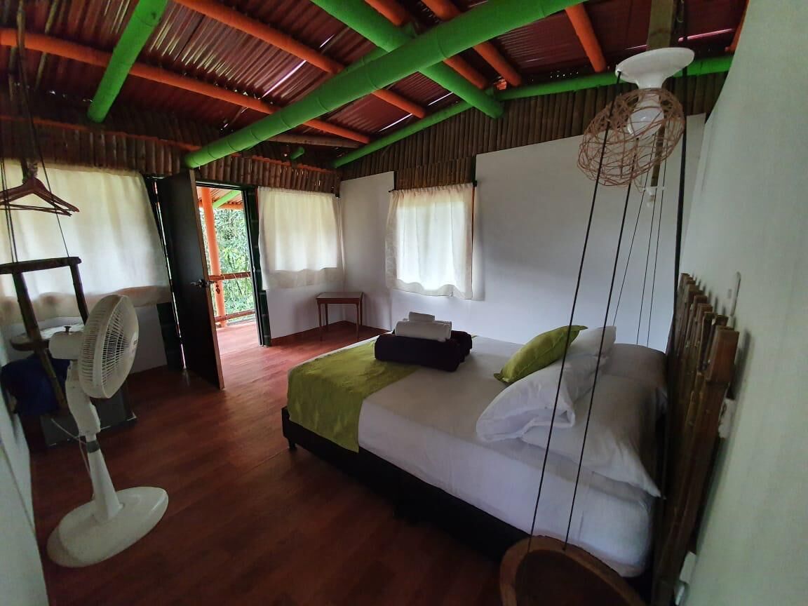 Una habitación con una cama, un ventilador, una mesa y una lámpara colgante.