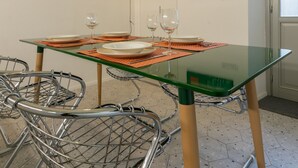 A dining area with a glass table, metal chairs, and a red accent wall.