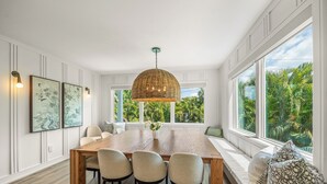 A dining room with a large wooden table, four chairs, a woven pendant light, and artwork on the walls. - Experience Luxury at Go with the Flow! Lazy River Pool, Rooftop Deck and Games! (Anna Maria)