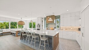A modern kitchen with a large island, bar stools, and pendant lighting. - Experience Luxury at Go with the Flow! Lazy River Pool, Rooftop Deck and Games! (Anna Maria)