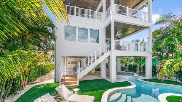 A modern two-story house with a pool, outdoor seating, and lush greenery. - Experience Luxury at Go with the Flow! Lazy River Pool, Rooftop Deck and Games! (Anna Maria)