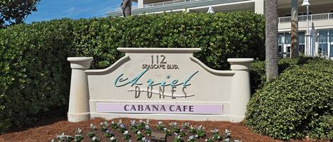 A sign for 'Cabana Cafe' at 112 Seascape Blvd. with a landscaped area in front.