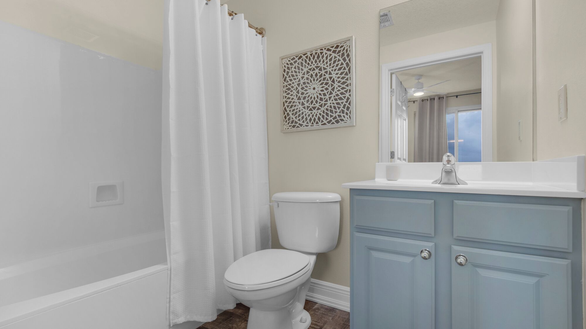 A bathroom with a shower, toilet, vanity, and a decorative wall piece.