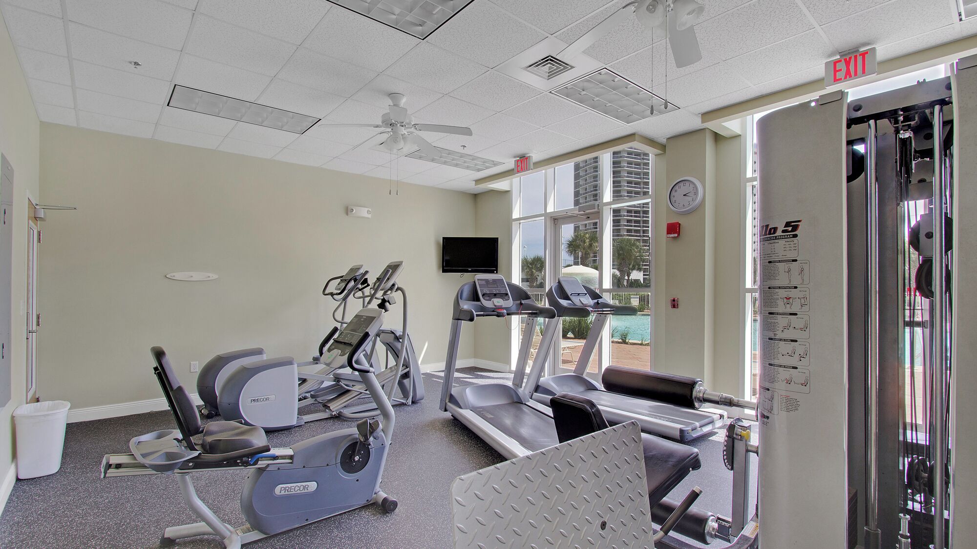 A gym with treadmills, elliptical machines, and a ceiling fan.