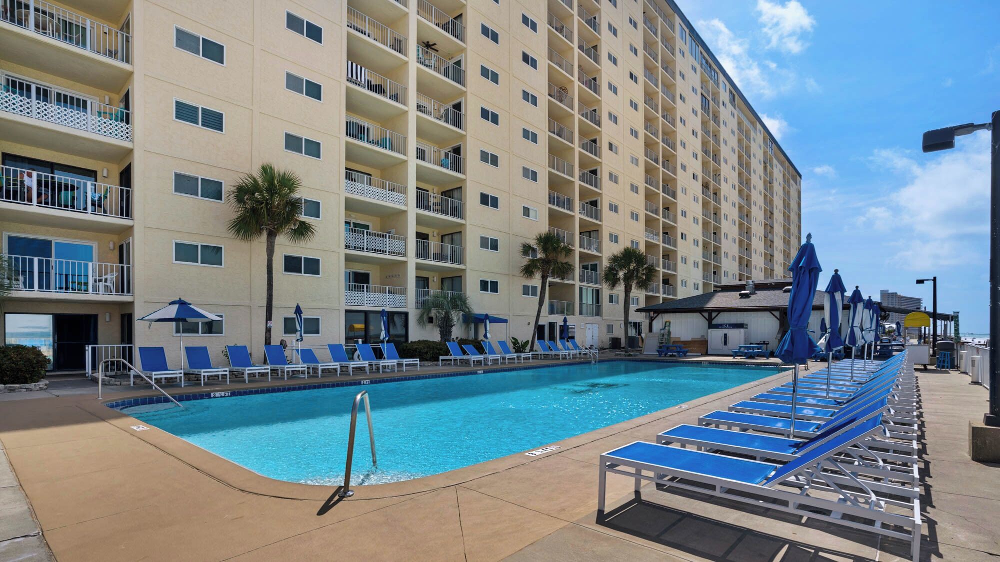 Un hotel con zona de piscina, varios balcones y vistas a la playa.
