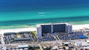 Luftaufnahme eines Hotels mit großem Parkplatz, Strand und freiem Blick auf den Ozean.