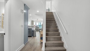 A modern kitchen with a central island, wooden flooring, and a staircase leading to an upper level. - Gulf-front in Destin! Community Pool, Minutes to Beach (Destin)
