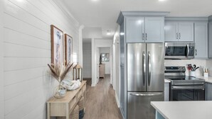 A modern kitchen with stainless steel appliances, a wooden countertop, and a hallway leading to a dining area. - Gulf-front in Destin! Community Pool, Minutes to Beach (Destin)