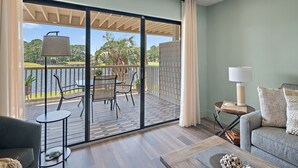 A balcony with a table and chairs, a sofa, and a lamp. - 1BD Bayside Condo at Sandestin, Golf Cart & Pool (Miramar Beach)