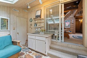 Een gezellige kamer met een stenen vloer, houten wanden, een wastafel en een blauwe bank.