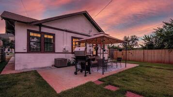 Une maison dotée d’un patio couvert, d’un barbecue et de mobilier d’extérieur.