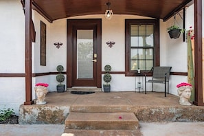 A house entrance with a wooden door, two potted plants, a bench, and a table with chairs. - Royal Estate Manor de Luxe (Abilene)