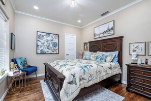 Un dormitorio con una cama grande, un aparador, una silla y obras de arte en las paredes.
