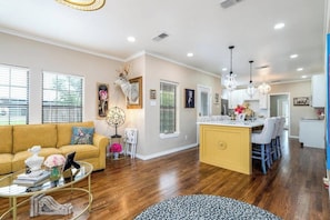 A spacious living room with a yellow sofa, a glass coffee table, and a leopard print rug. - Royal Estate Manor de Luxe (Abilene)