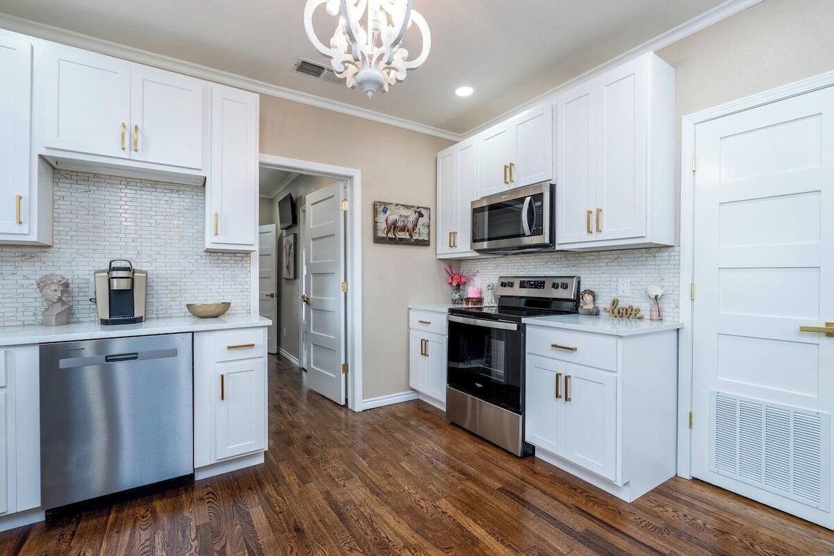 A kitchen with white cabinets, a stainless steel dishwasher, a microwave, and an oven.