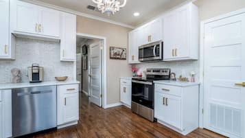 A kitchen with white cabinets, a stainless steel dishwasher, a microwave, and an oven.
